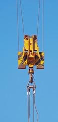 Crane hook hanging on steel ropes isolated on background sky