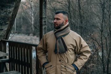 Young handsome man in autumn outdoor setting wearing fashionable clothing. Fashion model posing in autumn scenery.