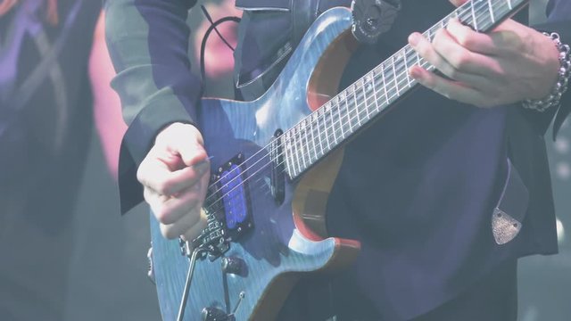A virtuoso guitarist playing an electric guitar on stage with flashing LED lights.