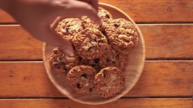 The scramble hand picked the cookie out of the wooden plate.
