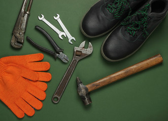 Set of professional work tools and boots  on green background. Top view.