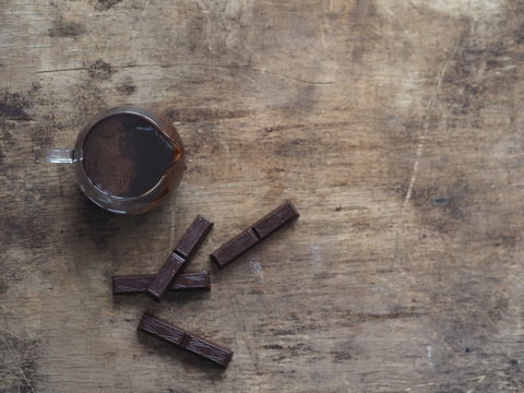Hot chocolate icing for pouring confectionery. Pieces of chocolate on a wooden ancient background.