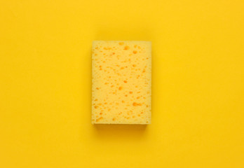 Ready for cleaning! Sponge on a yellow background. Minimalism. Top view