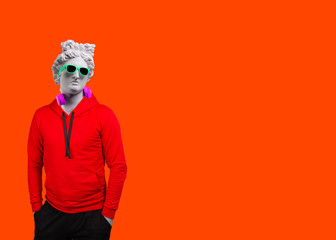 Plaster statue of Apollo's in blue sunglasses and earphone. Minimal concept art. On a orange background.