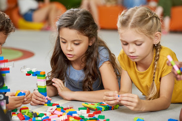 Group of children playing toy blocks. Four little friends in playroom. Happy time together in...