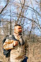 Young handsome man with autumn tree in background. Handsome man in the park. Autumn scenery