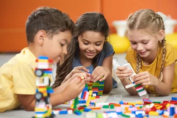 Fotobehang Lego Happy kids playing with constructor at kindergarten. Children playing with colorful plastic bricks on the floor. Preschool kids having fun.  © DenisProduction.com