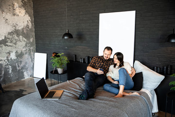 Naklejka premium Couple with phone in casual clothes on bed.