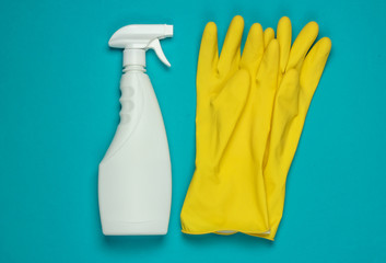 White bottle of spray for cleaning, gloves on blue background. Top view. Minimalism