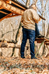 Young fashion man walking in autumn park with backpack. Short bearded man looking and enjoying the nature.