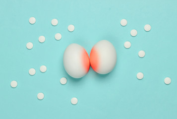 Naklejka na ściany i meble Treatment of prostatitis. Inflammation of the prostate. Allegorical photo of chicken eggs with red inflammation and pills on a blue background.