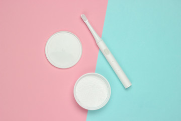 Fototapeta na wymiar Modern electric toothbrush and tooth powder on pink blue pastel background. Dental care concept. Top view. Minimalism