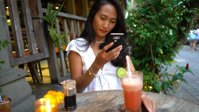 Happy asian woman taking photo of drink with cellphone in cafe