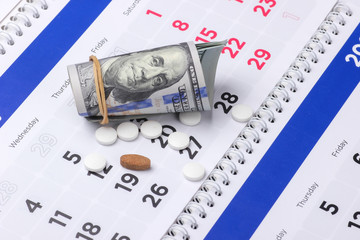 Pills with dollar bills on the calendar. Healthcare and medicine concept