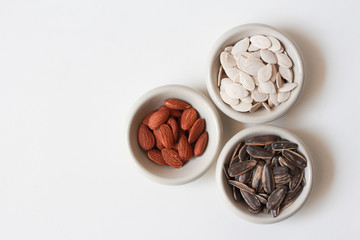 Pumpkin seeds, sunflower seeds and almond in bowl with copy space on white background for product or text. Top view.