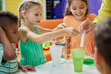 Kids doing chemical experiment at entertainment center. Flasks with colorful liquid on table....