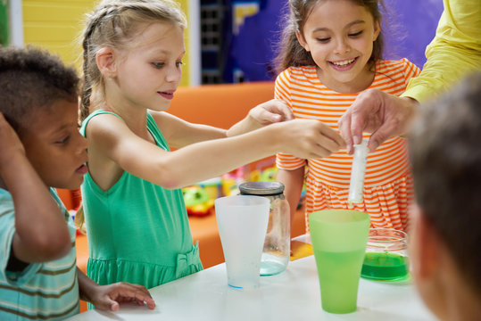 Kids doing chemical experiment at entertainment center. Flasks with colorful liquid on table. Childrens party entertainment.