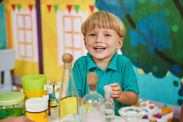 Happy smiling kid in playroom of entertainment center. Laboratory glassware flasks on the table....