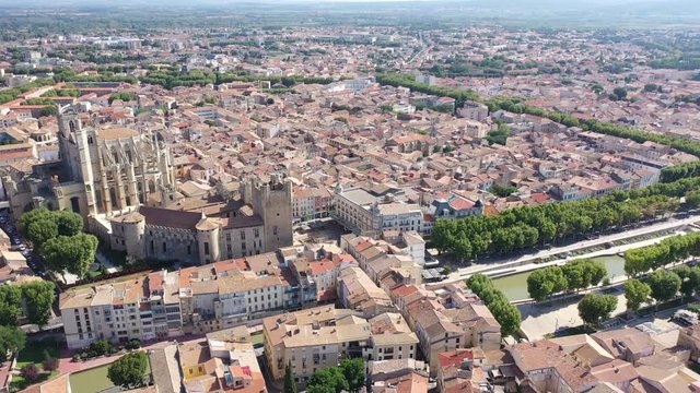 Scenic panoramic aerial view of residential areas of Narbonne with medieval Roman Catholic Cathedral on sunny summer day, France