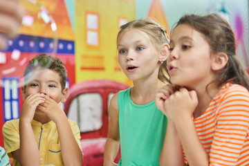 Happy kids at chemistry show in entertainment center. Three excited kids having fun in play room.