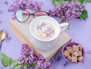 Obraz na płótnie Canvas Cappuccino, book with glasses, violet lilac flowers, morning concept