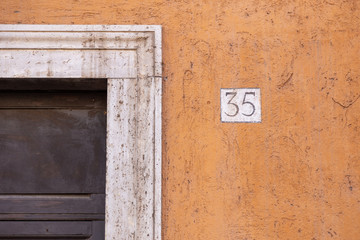 number 35, ancient house number plate on brick wall, Italy