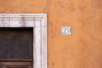 Obraz na płótnie Canvas number 29, ancient house number plate on brick wall, Italy