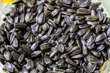 Black fried seeds in a plate close-up.