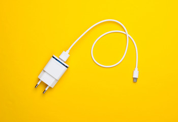 Charger with cable on a yellow background. Top view