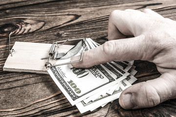 mousetrap, human hand, us dollar bills on wooden background. financial trap.