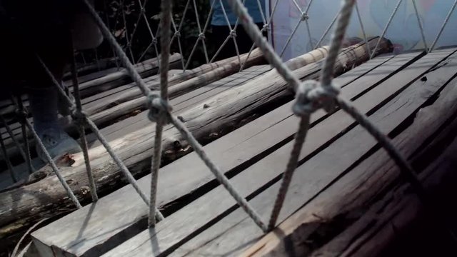 Children feet walk on wooden bridge at playground 
