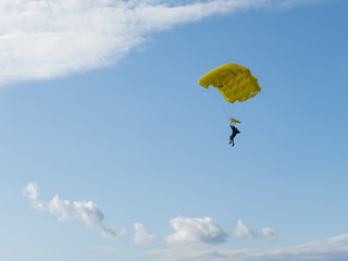 Parachuter descending with parachute against blue sky. Skydiver in the sky. People under parachute in the sky.