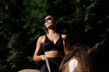 Young pretty girl - riding a horse, equestrian sport in summer time.Beautiful young woman riding a...