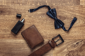 Men's wedding accessories on the floor. Groom. Butterfly tie, wallet, belt, perfume bottle. Top view