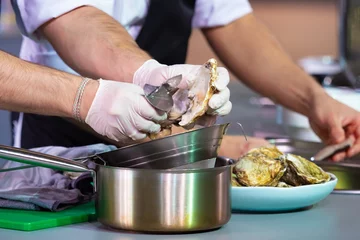 Foto op Canvas Knife for opening oysters. Cook is preparing a dish with oysters. Cooking mollusks for serving. Inventory for disclosing shells. Cook takes out an oyster and throws it on a sieve. Seafood sale © Grispb