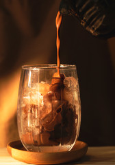Cocoa is pouring into a glass with ice.