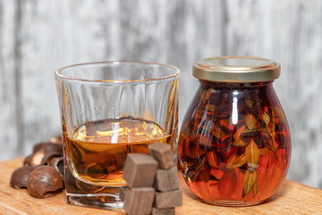 Glass of poured homemade whiskey with ingredients for cooking.