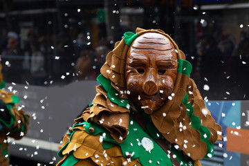 Parade on the occasion of carnival with a traditional expressive wooden mask from the south of Germany in a confetti rain
