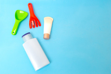 Sunscreen cream spf lotion to remedy kids skin from sun with colorful water toys on blue water surface of pool, top view. Concept ultraviolet protection product, summer children cosmetics.