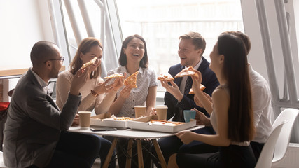 Happy diverse colleagues enjoy pizza having fun at lunch break