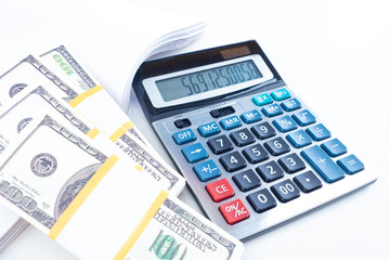 Bundles of money next to a calculator. Costing. Money to pay bills. Concept - dollars are prepared to pay taxes. Accounting audit. Counting balances in the company account. Calculate available money