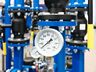 Close up of manometer, pipe, flow meter, water pumps and valves of heating system in a boiler room