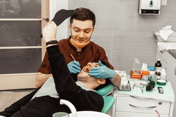 A young male dentist doctor treats a patient. Medical manipulations in dentistry, surgery....