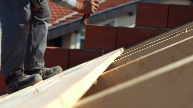 roofer working on roof structure of building on construction sit