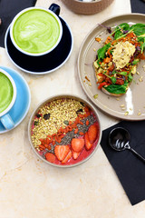 raw healthy food breakfast. smoothie bowl, toast with hummus, and matcha latte green tea cup on the table. vertical photo
