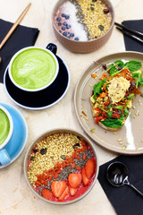 raw healthy food breakfast. smoothie bowl, toast with hummus, and matcha latte green tea cup on the table. vertical photo