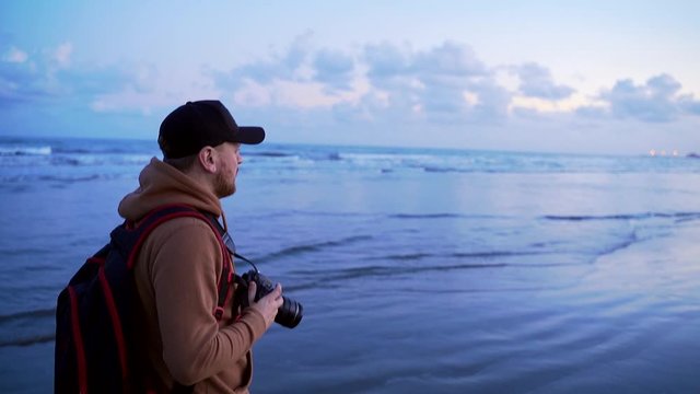 young stylish travel blogger photographer walks along the seaside or ocean. Photographing landscapes past a man running