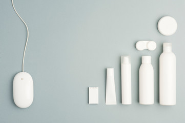 Collection of various beauty hygiene containers on soft gray background. Wired computer mouse, space to fill.top view