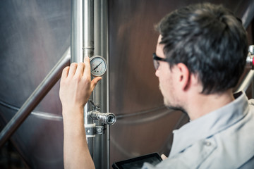 Technician monitoring and documenting readings of gauges on a steel tank. Red Lodge, Montana, USA