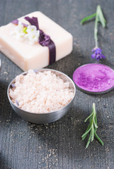 beauty product samples with fresh purple and blue dried lavenders, bath salts and massage pouches on dark wood table background